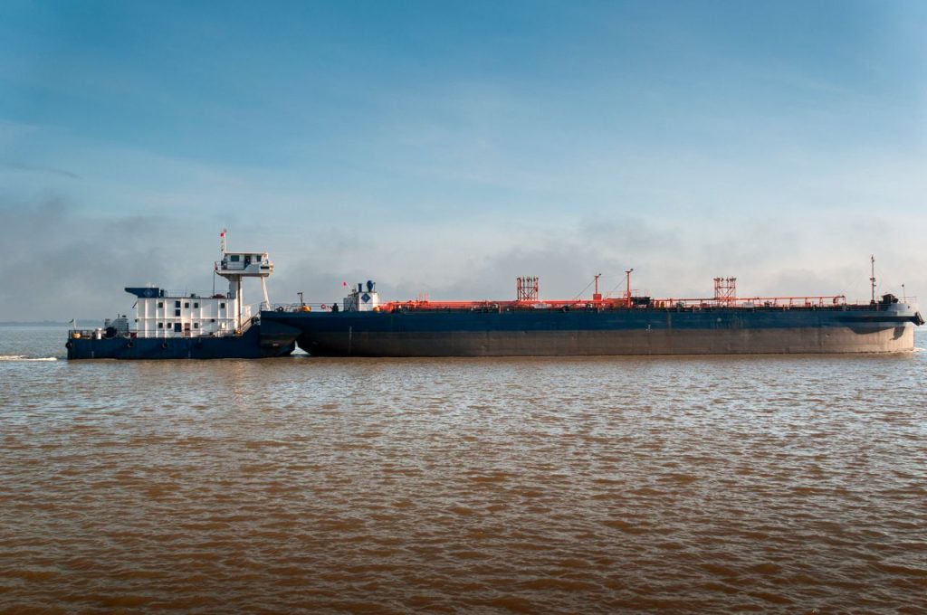 A massive blue cargo ship sailing on calm waters under a clear sky.